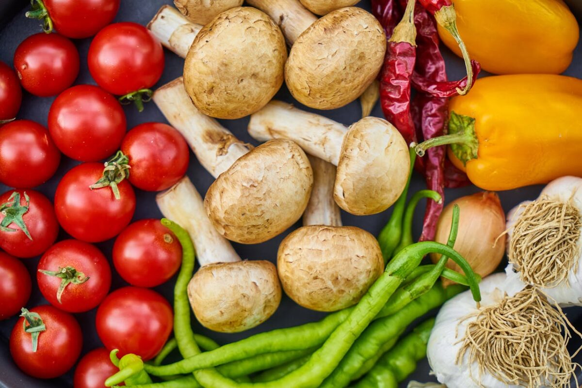 about-us-02 A vibrant assortment of fresh vegetables and mushrooms arranged in a flat lay.